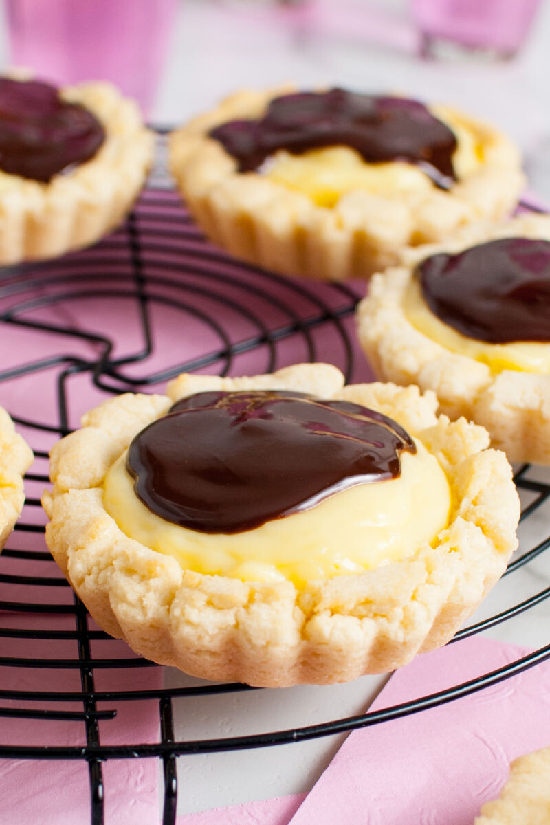 close up side view of copycat crumbl boston cream pie cookies on a wire rack