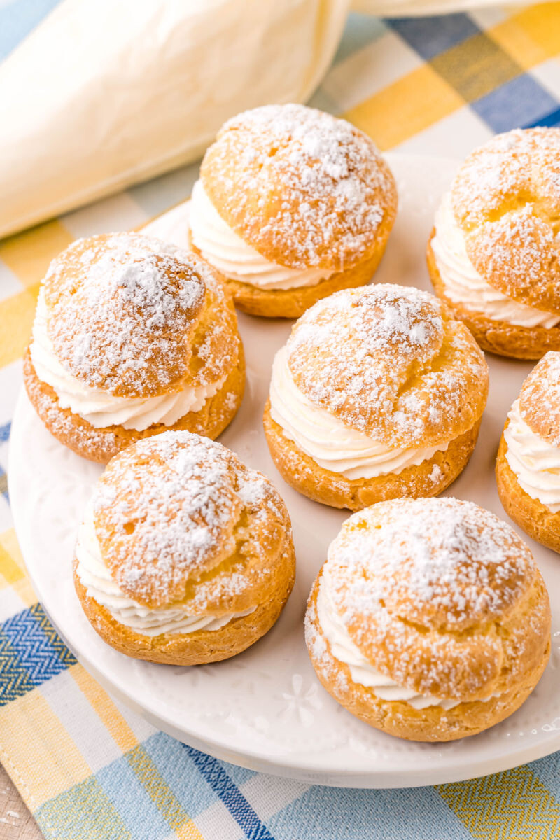 plate of cream puffs filled with whipped cream and dusted with powdered sugar