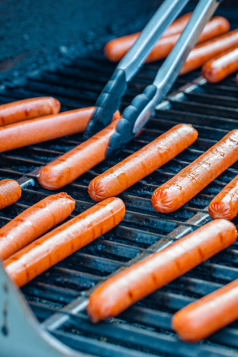hot dogs being cooked on a grill