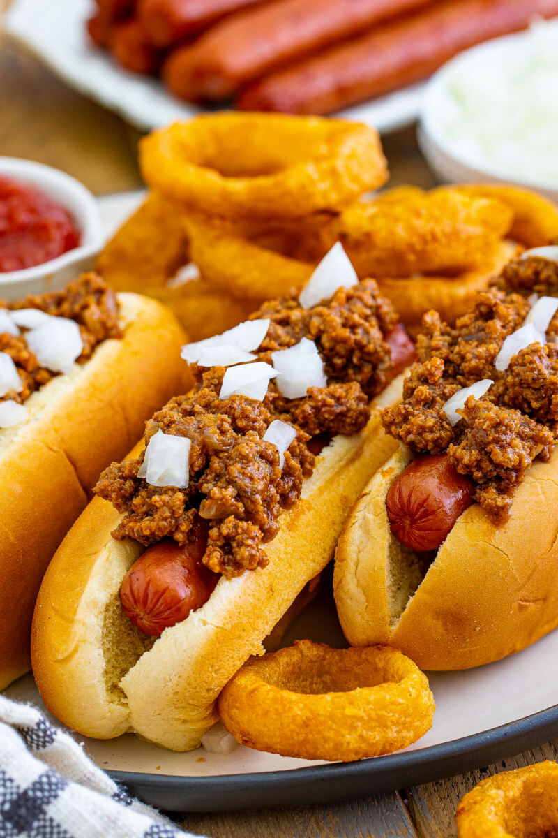 hot dogs on a plate with hot dog chili and onions on top