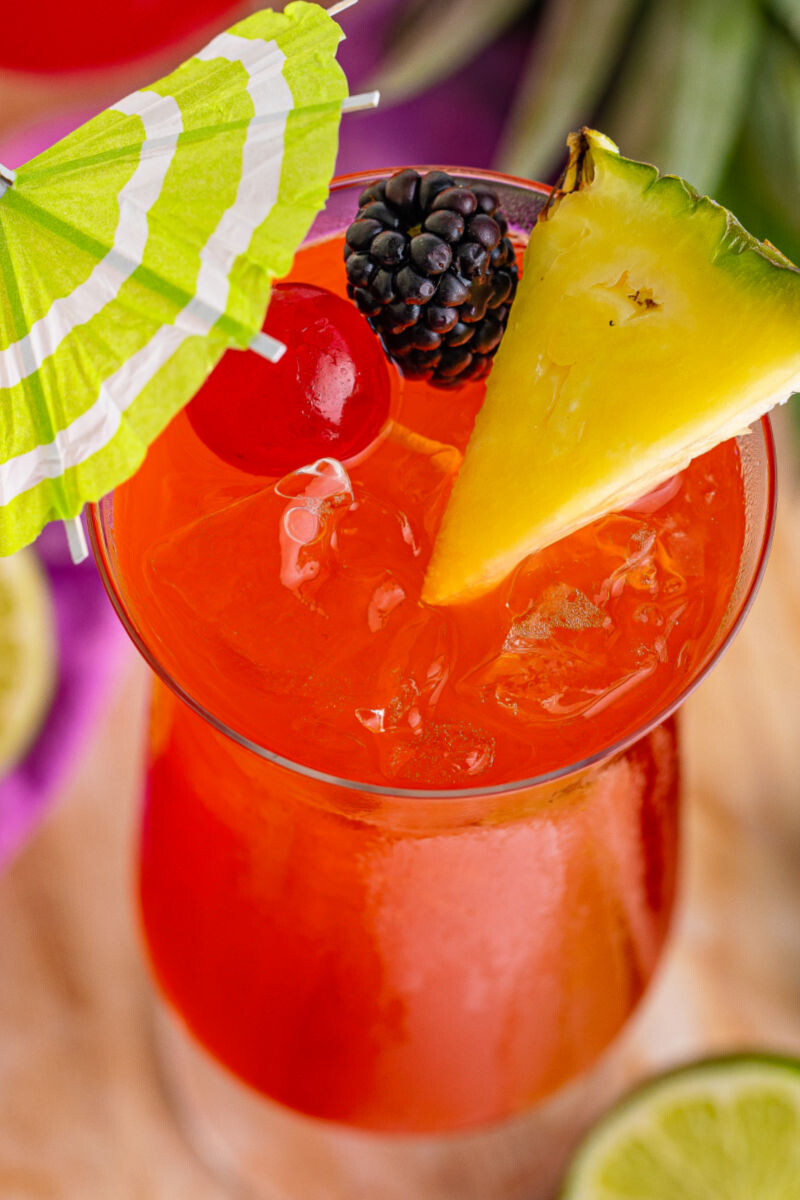 close up looking down at a rum runner with fruit and umbrella garnish