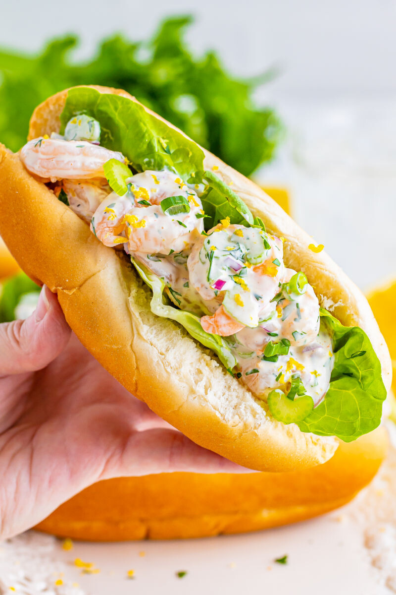 close up of a hand holding a shrimp salad sandwich