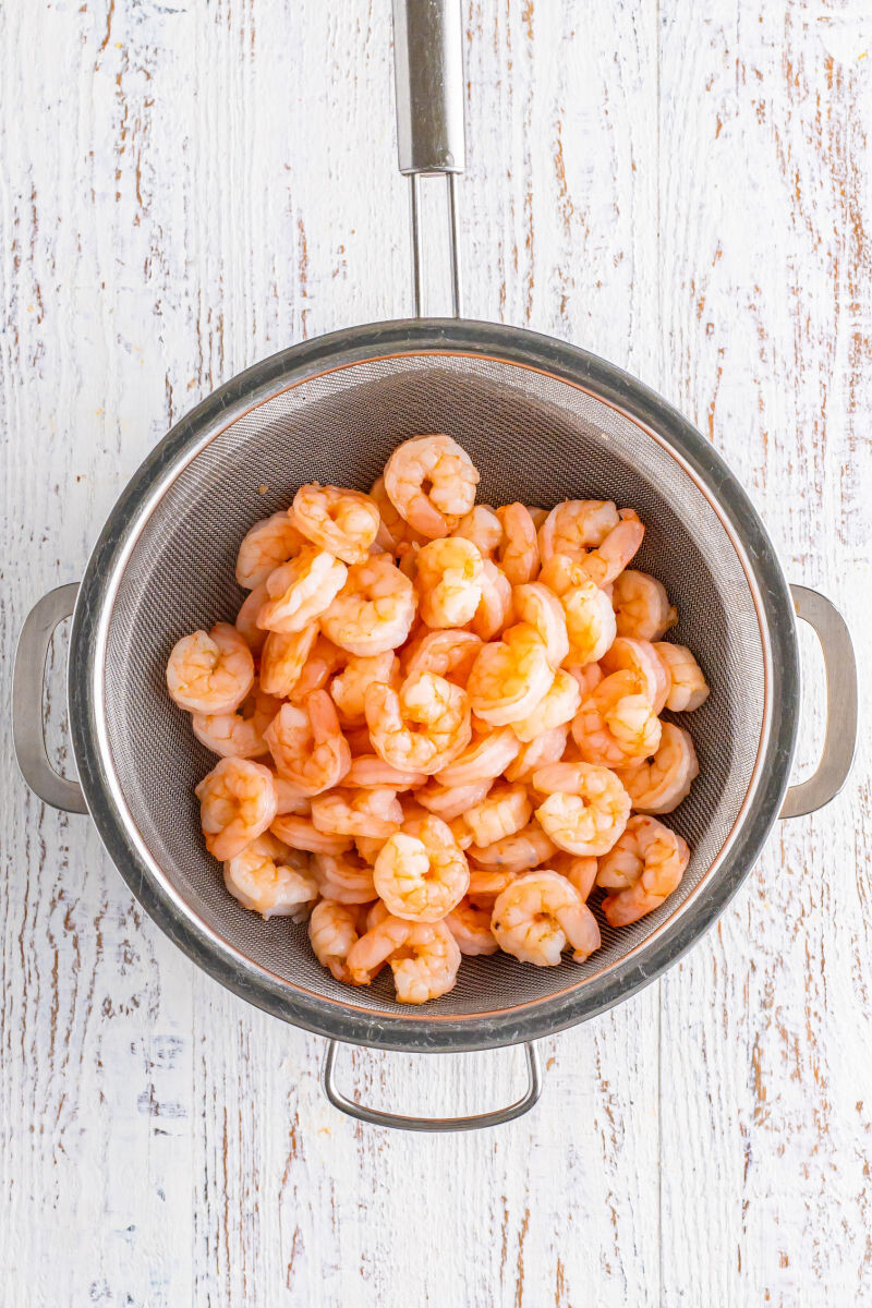 cooked shrimp in a strainer over a pot