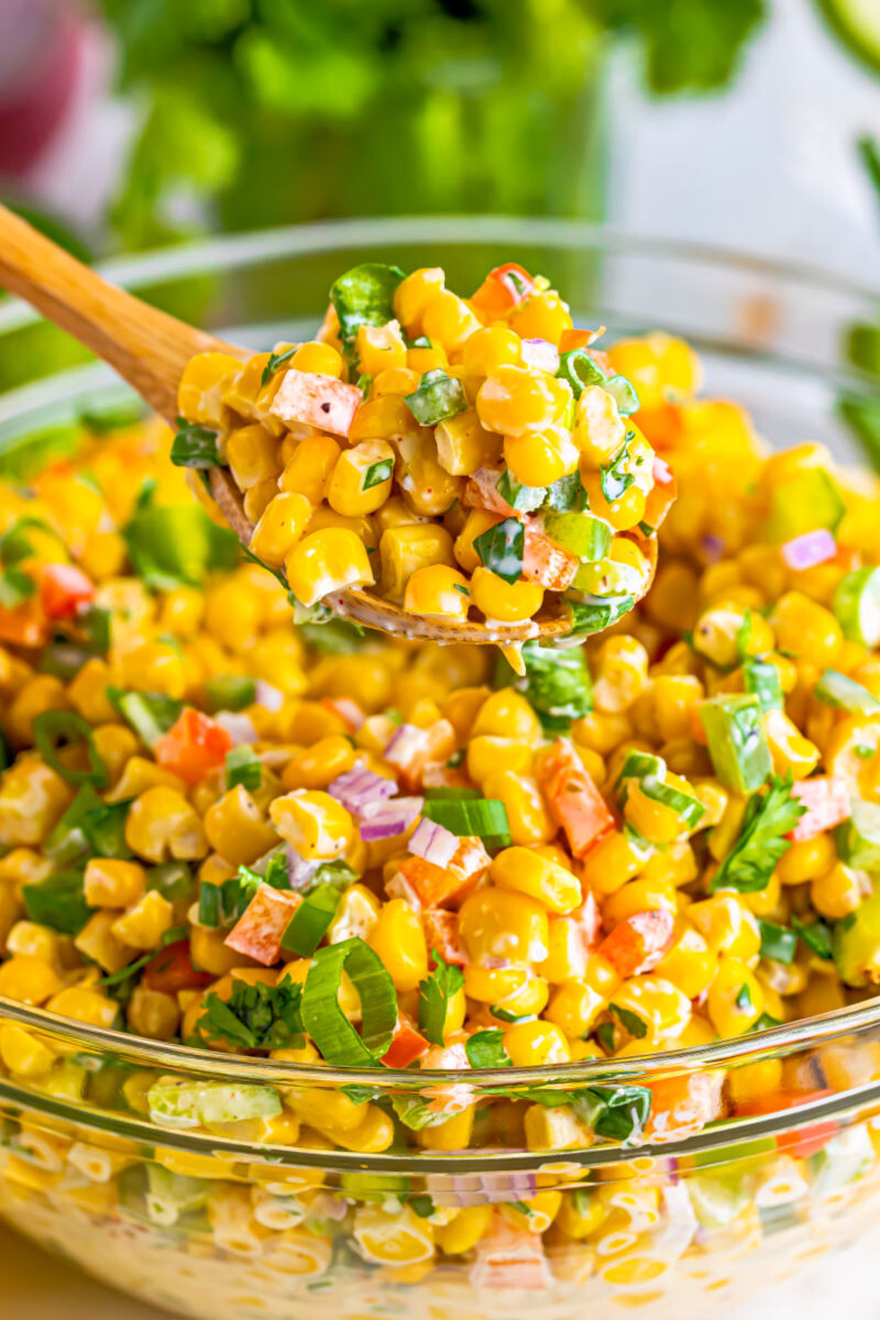 close up of a spoonful of tex-mex corn salad over the bowl
