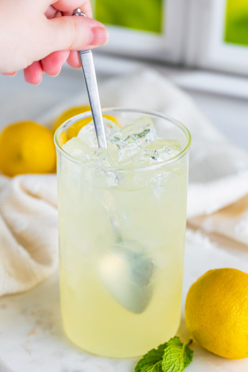 glass of homemade lemonade being stirred with a spoon