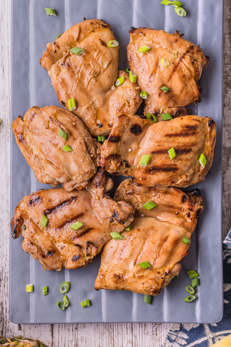 grilled huli huli chicken on a platter garnished with sliced green onions