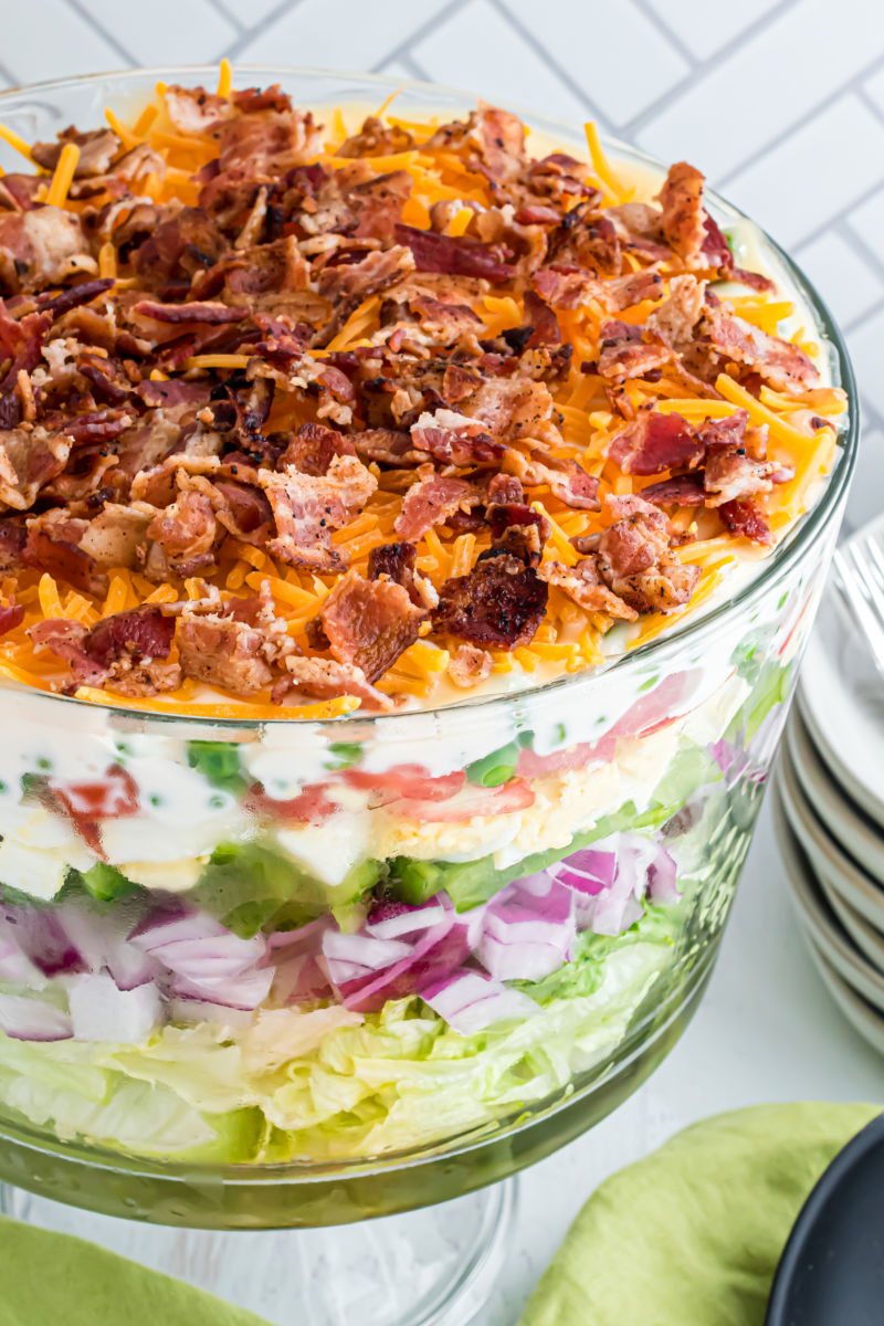 angle view looking down at a 7 layer salad with shredded cheddar and bacon on top