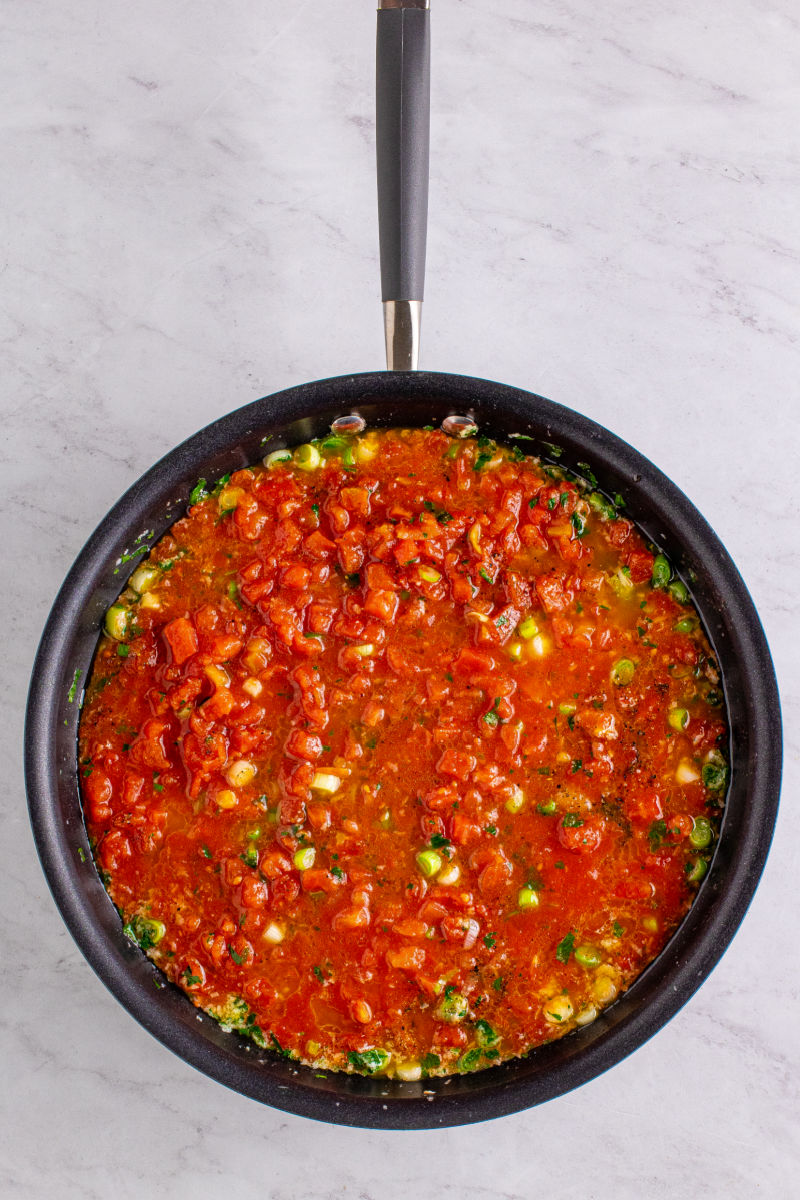 canned petites diced tomatoes added to the garlic and green onions in a skillet