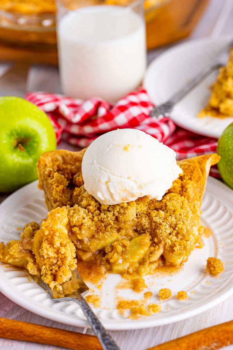 bite of Apple Crumb Pie on a fork next to a slice of pie on a plate