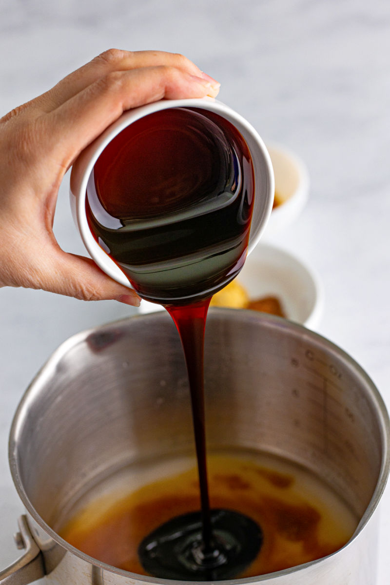 molasses being poured into a saucepan with water, sugar, dark brown sugar