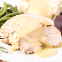 square image of turkey gravy poured over sliced turkey breast