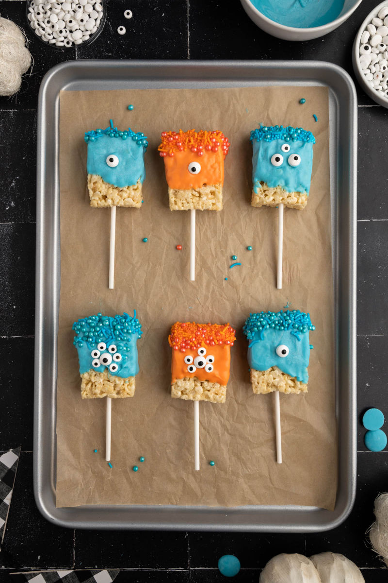 blue and orange monster rice krispie treats on a baking sheet lined with parchment paper
