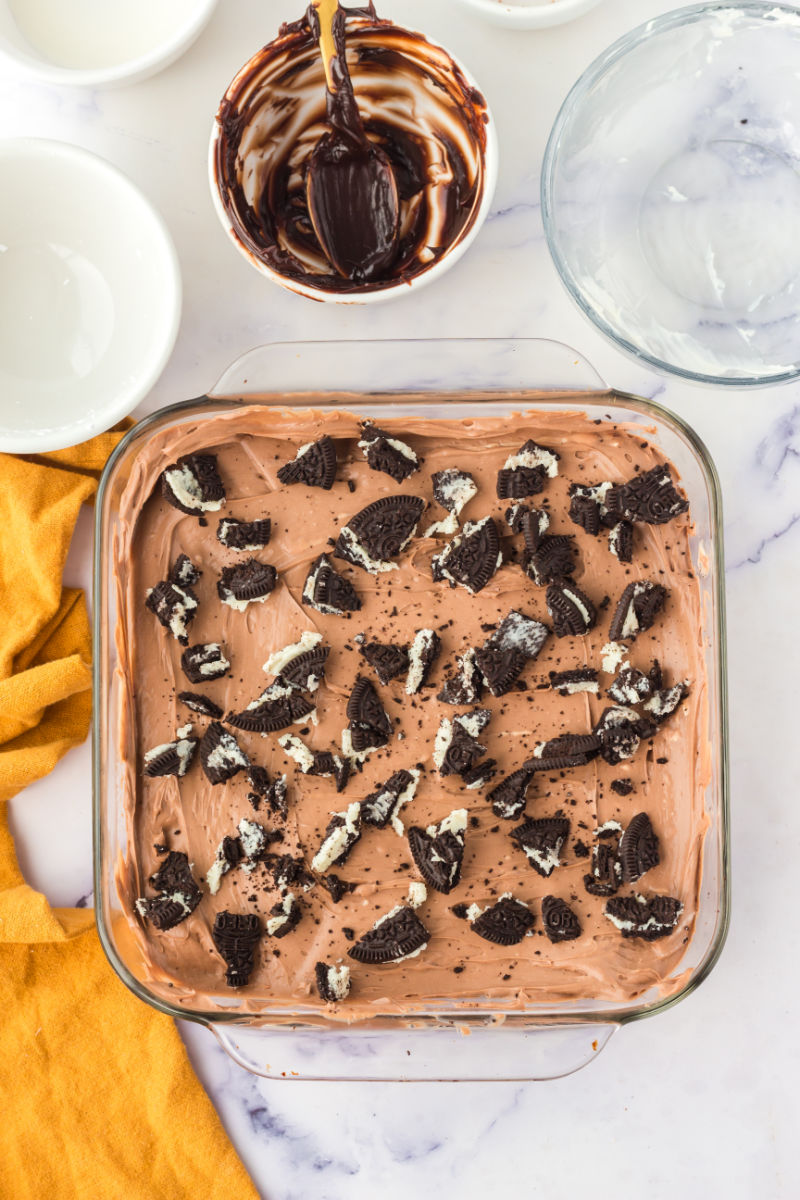no bake chocolate cheesecake in a square dish topped with crumbled Oreo cookies