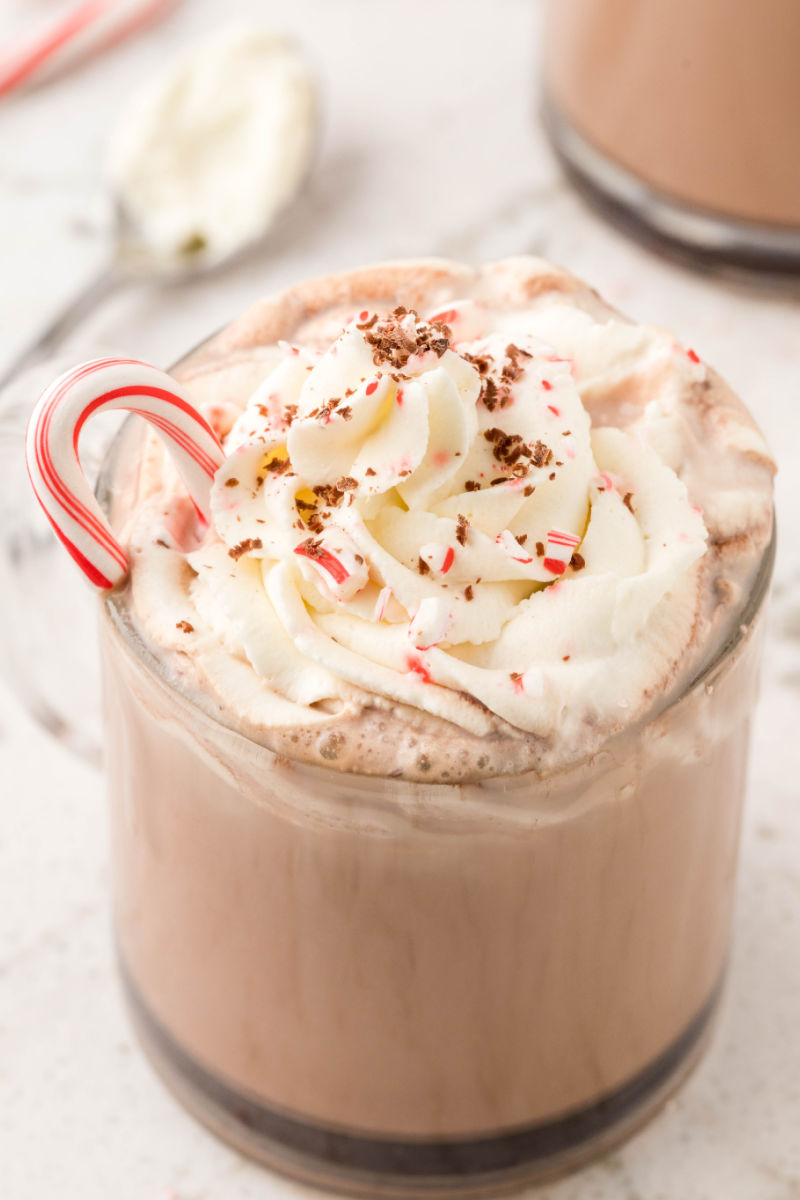 angled view of peppermint mocha with a small candy cane stuck into the whipped cream for garnish