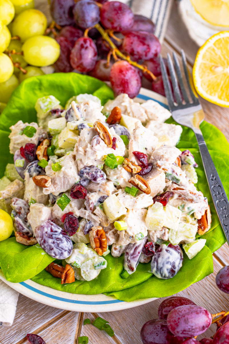close up of turkey waldorf salad served over lettuce leaves on a plate with a fork