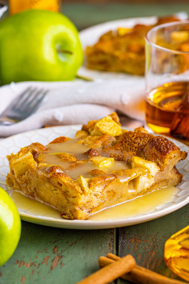 side view of fireball apple bread pudding on a plate with sauce