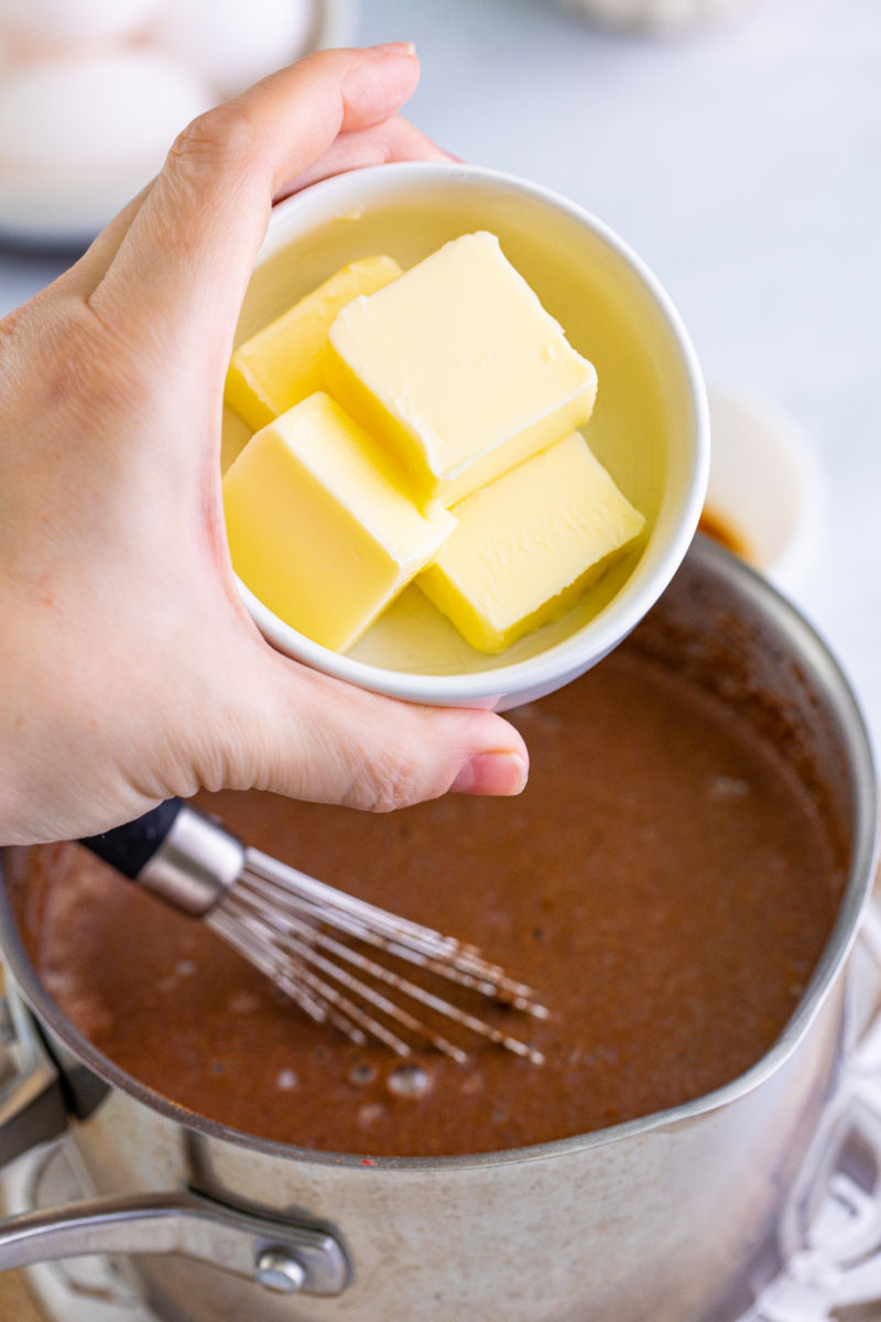 butter being added to a saucepan with fireball custard for bread pudding