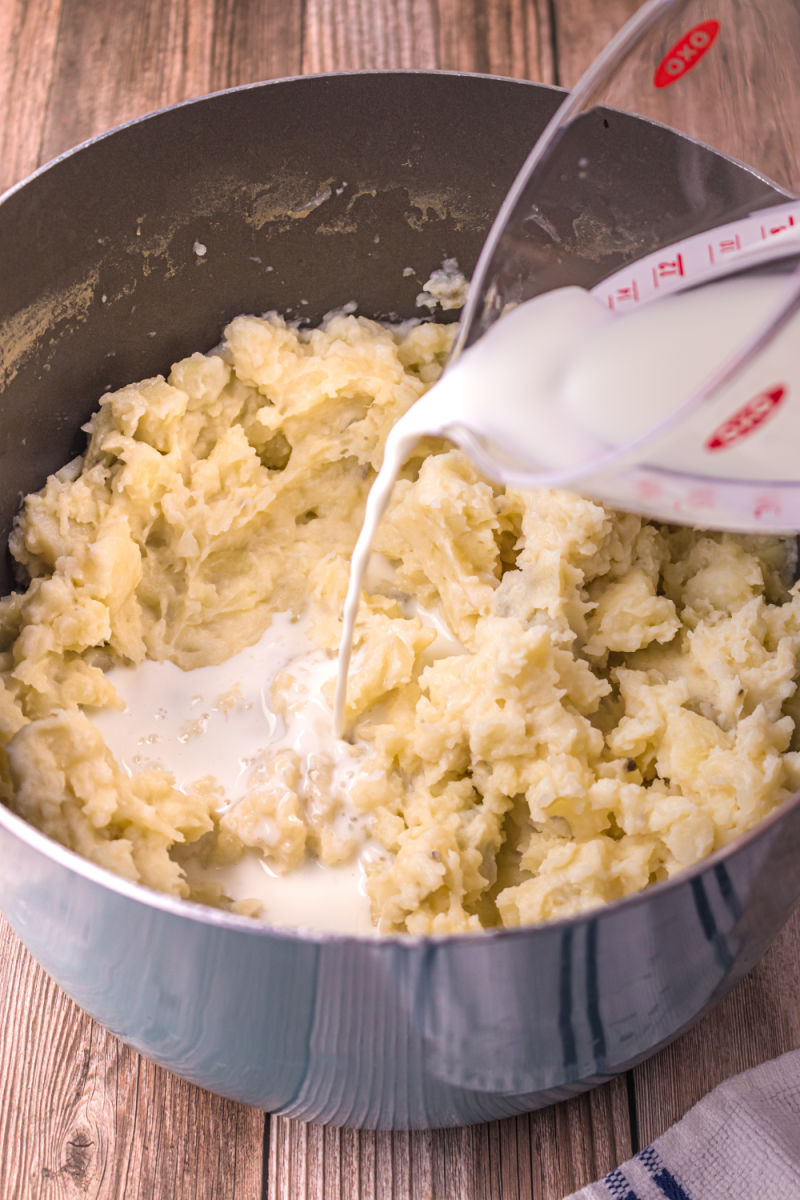 milk being poured into mashed potatoes