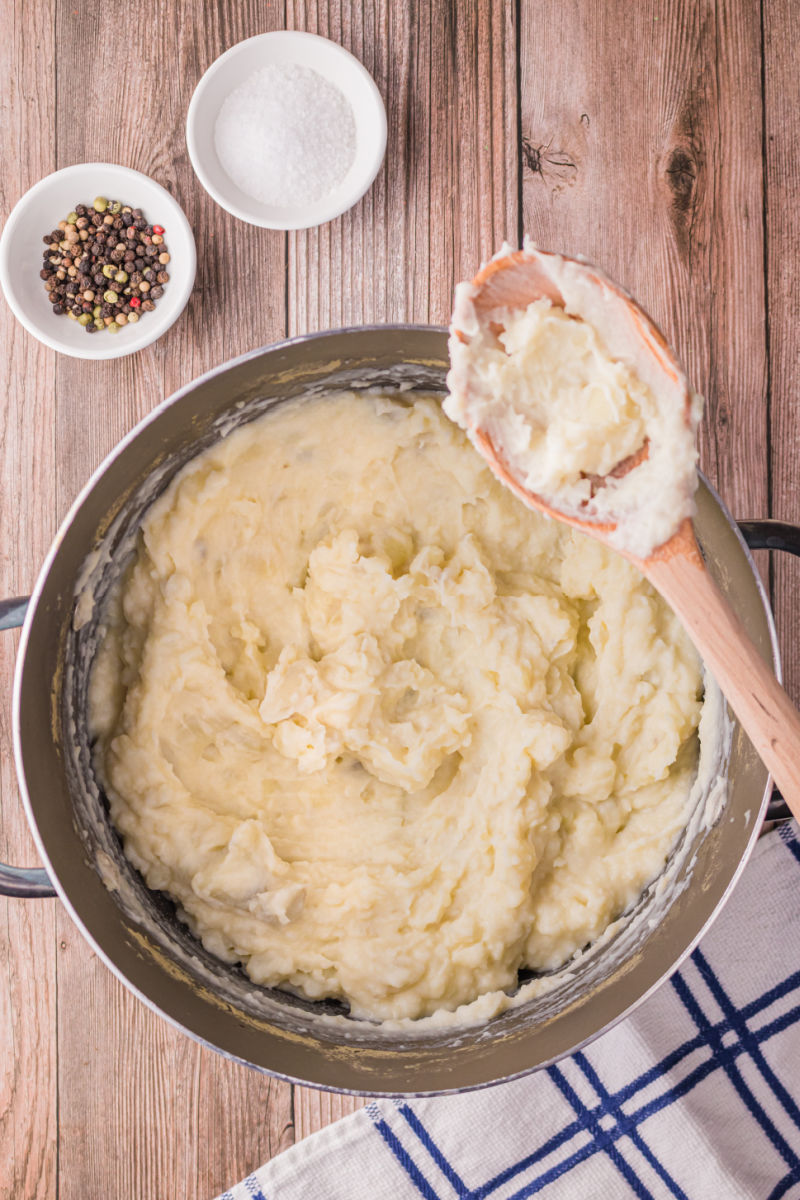 mashed potatoes in a large pot with a wooden spoon