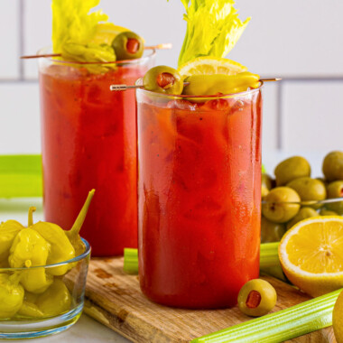 square image of two bloody mary cocktails on a wood board
