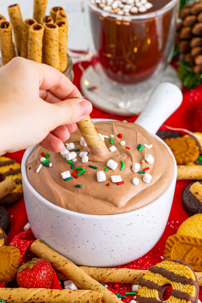 pirouette cookie being dipped into a bowl of hot cocoa dip