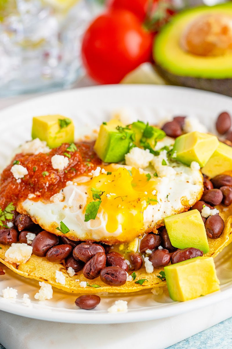 close up of huevos rancheros with the egg yolk broken open and running over the beans