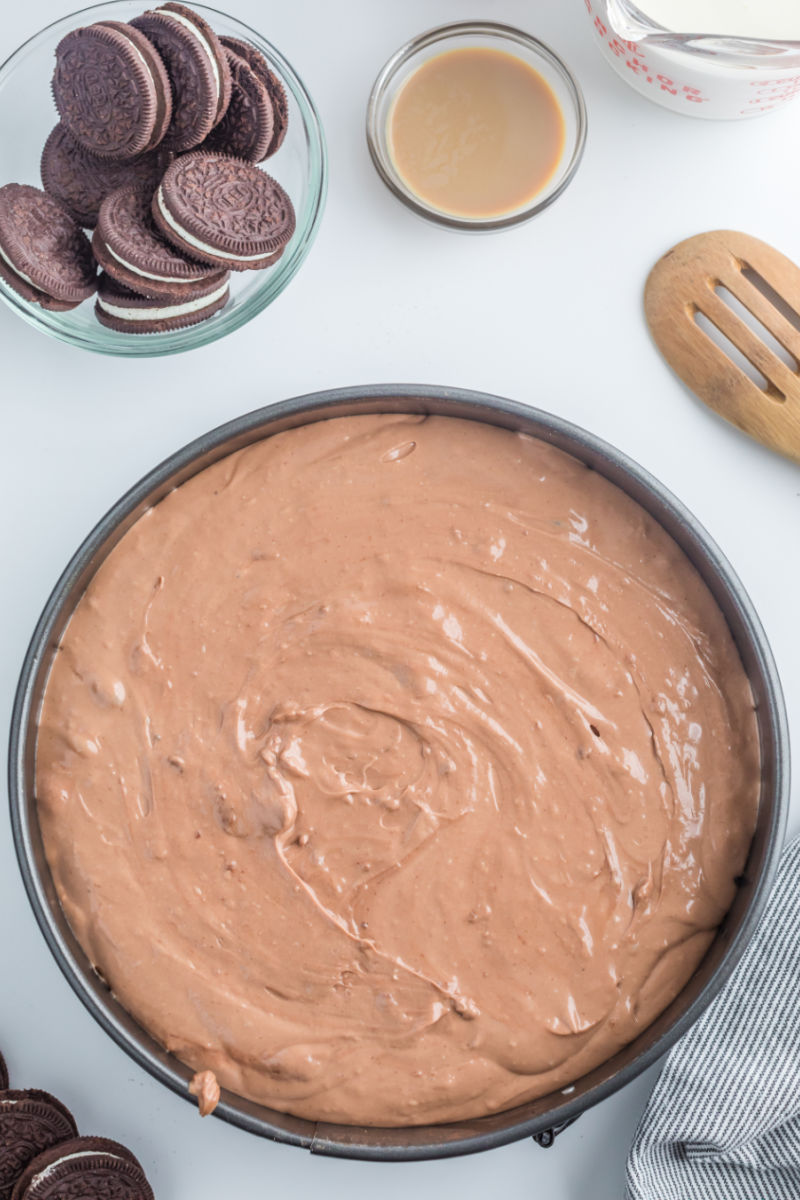 chocolate baileys cheesecake filling spread over the oreo crust in a spring form pan