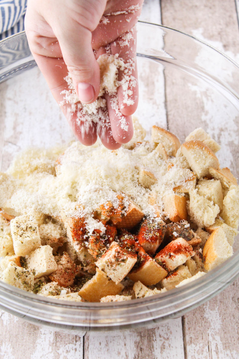 garlic oil, garlic, paprika, basil, oregano, salt, pepper, and grated parmesan added to a bowl of stale french bread cubes