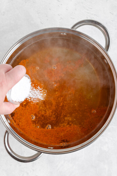 salt being added to a pot with hot water and Old Bar seasoning