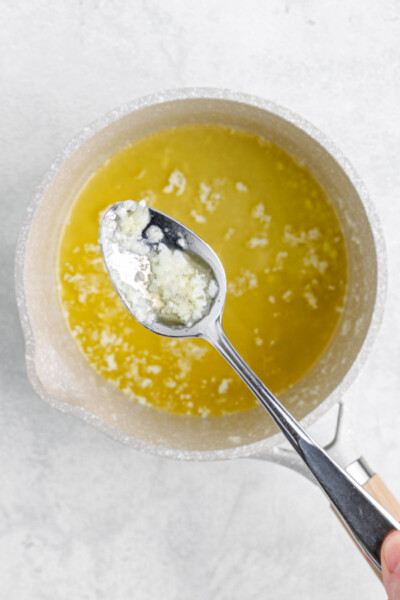 milk solids being spooned out of a pot of butter to clarify it