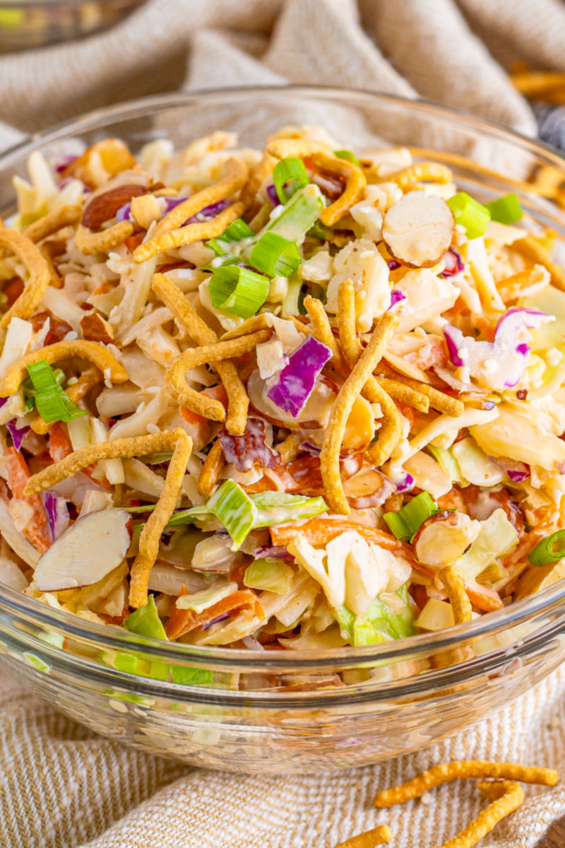 close up of creamy asian slaw topped with green onions, chow mein noodles, and sesame seeds