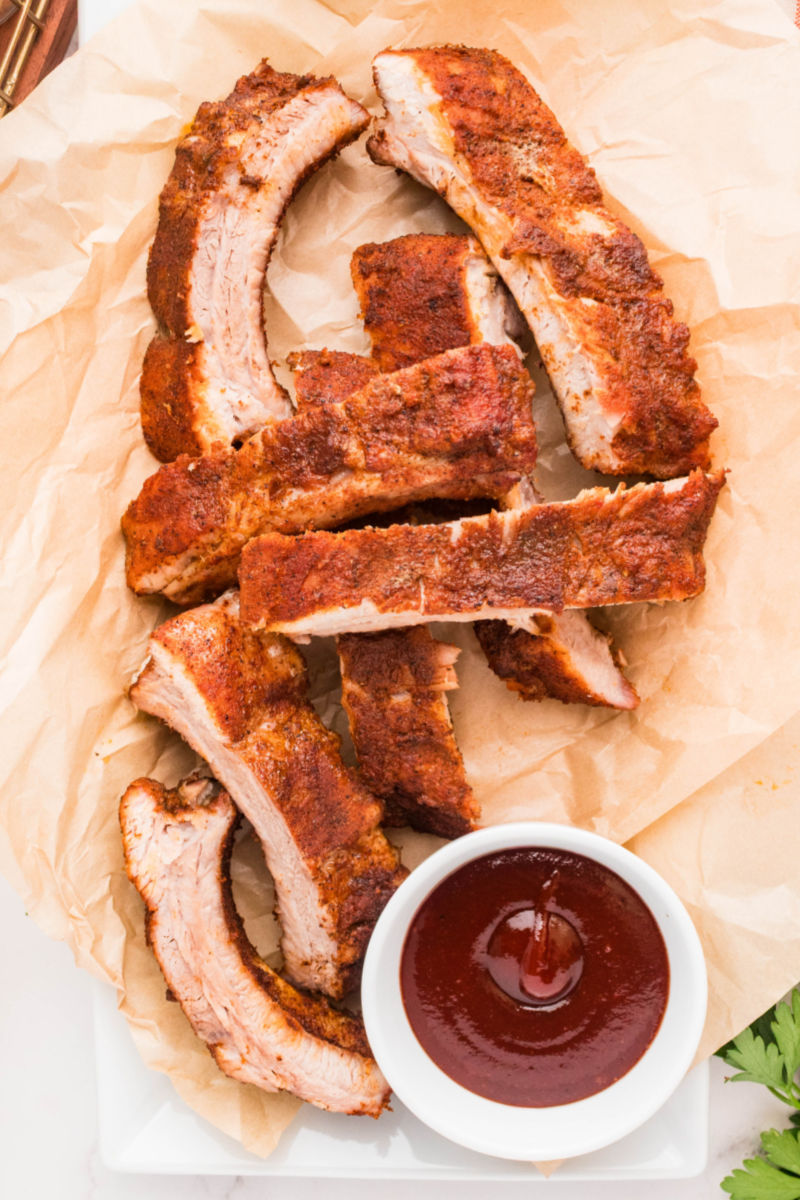 dry rub ribs in a basket next to a bowl of bbq sauce for dipping