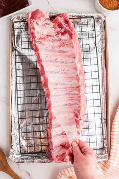 membrane being remove from the back of a rack of pork ribs