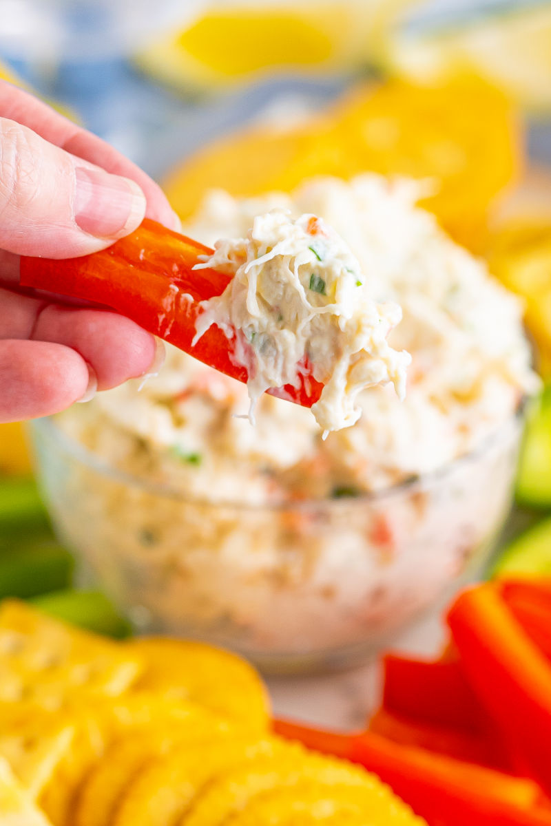 hand holding a bell peppers trip that's been dipped into cold crab dip