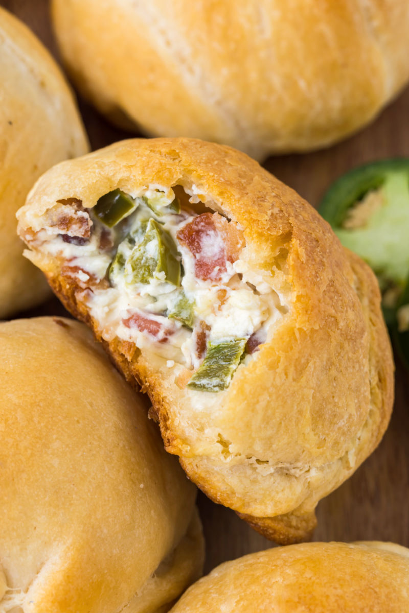 close up of a jalapeno popper bite with a bite taken out to show to filling