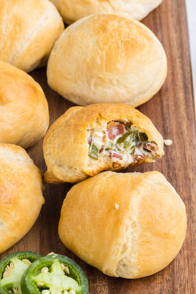 jalapeno popper bites on a wooden serving tray with a bite take out of one