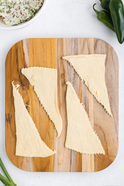 refrigerated crescent roll dough separated into triangles on a wooden cutting board