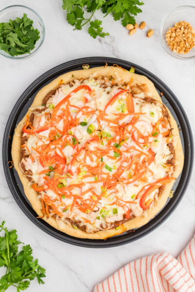 baked thai chicken pizza on a pizza pan