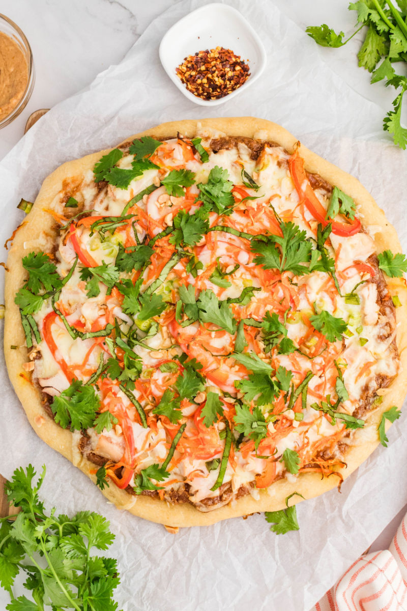 whole thai chicken pizza on a piece of parchment paper