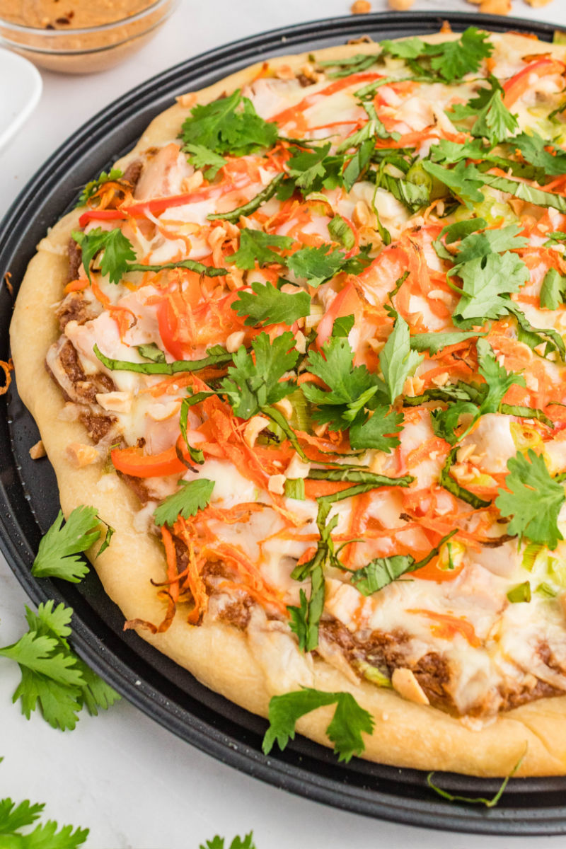 angled view of thai chicken pizza on a pizza pan after baking