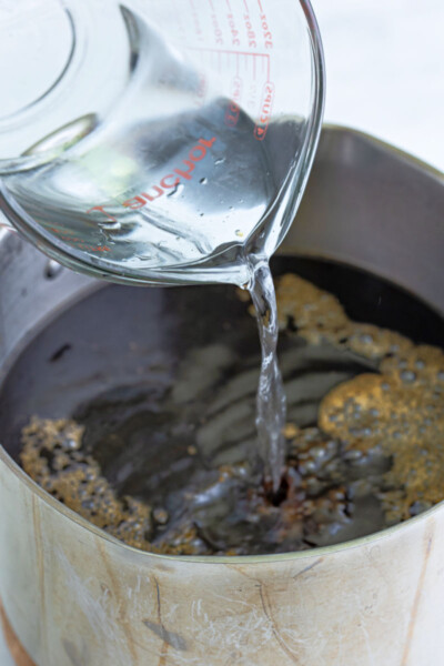 white rum being poured into a pot of homemade kahlua base
