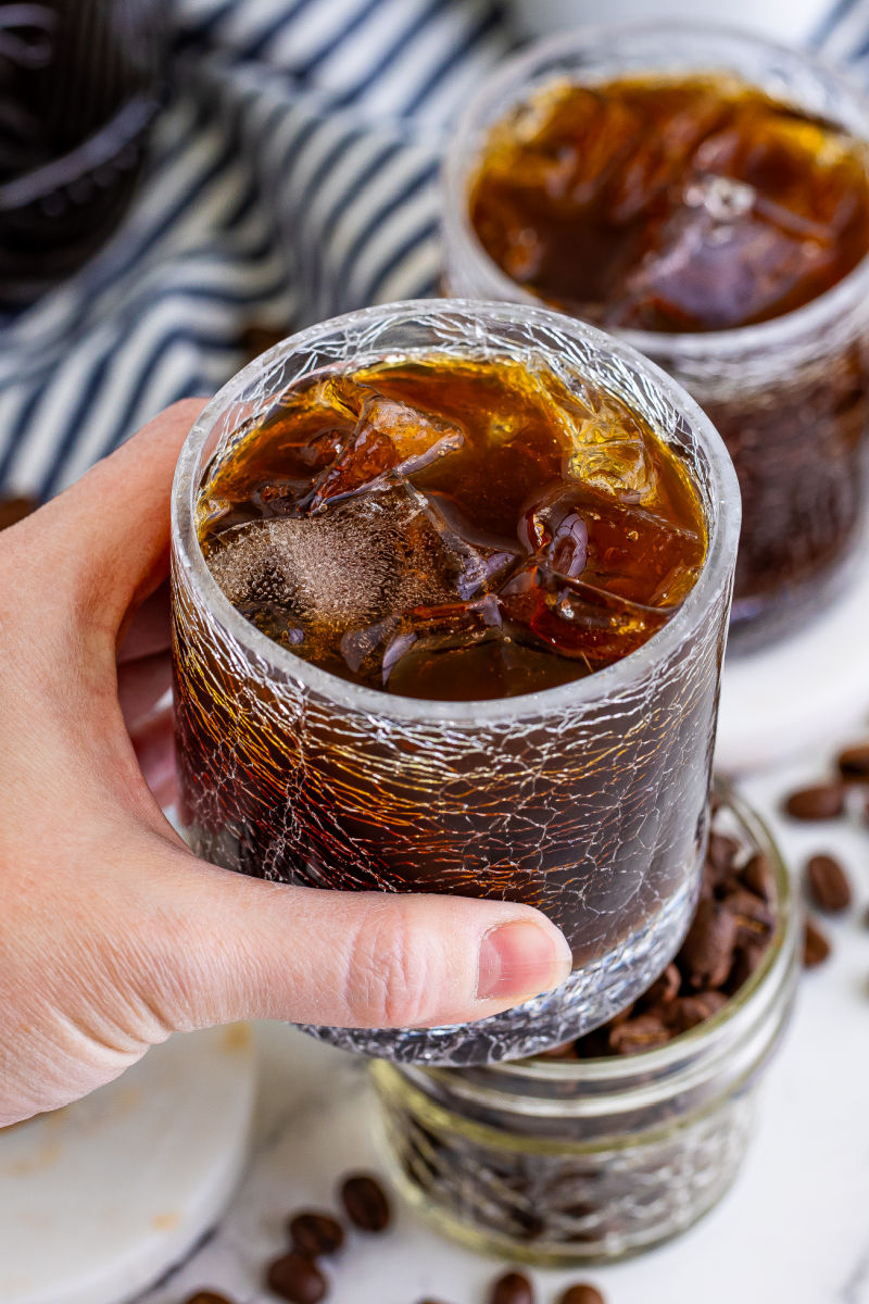 looking down into a glass of coffee liqueur being held by a hand